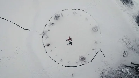 Aerial view: Couple start making snow angels Stockbeeldmateriaal 94283076