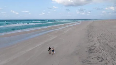 Aerial view of couple walking on empty sandy beach Stock Photos