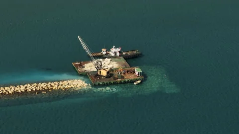 Aerial view of a crane loading stones onto a barge in the sea. Stock Footage 234523233
