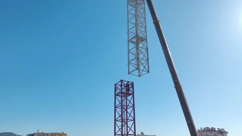 Aerial View: Crane operator assembles components and climbs high ladders against Stock Footage 296021055