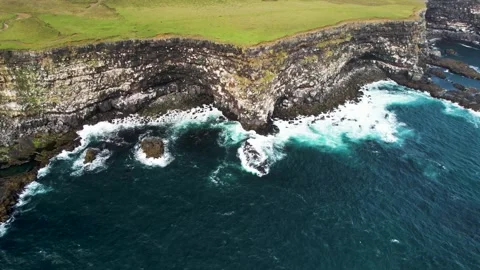 Aerial view of crispy waves breaking on the cliffs along the coastline in Stock Footage 242322352