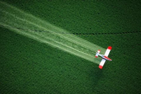 Aerial view of a crop duster or aerial applicator, flying low, and spraying a Stock Photos