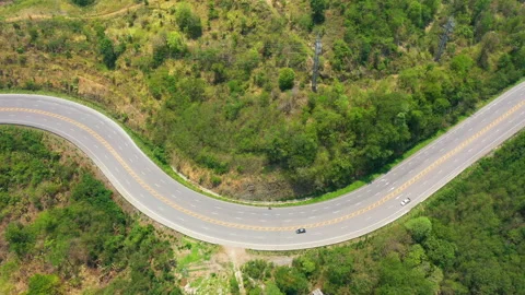Aerial view, curve road through forest with car moving. Tilt up shot. Stock Footage 200869653
