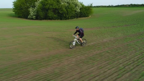 Aerial view. Cyclist rides on spring field. Video stock 129628524