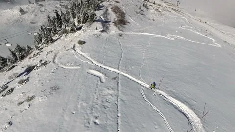 Aerial view. cyclist in yellow jacket on mountain bike going downhill snowy path Video stock 169540608
