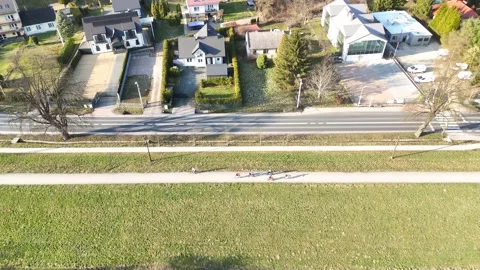 Aerial view of cyclists riding along a bike path beside a road, surrounded by Stock Footage 335885020