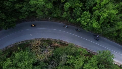 Aerial view of cyclists on a winding road through a dense forest, Bulgaria. Stock Footage 334168424
