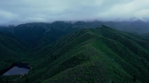 Aerial view of a dam below a mist-covered mountain ridge Stock Footage 342335669