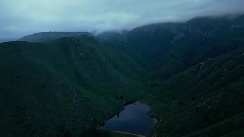 Aerial view of a dam in a deep valley between mist-covered mountains Stock Footage 342336081
