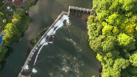 Aerial view of a dam on a river, with lush green trees lining the banks. Th.. Stock Footage 340545949