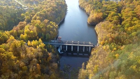 Aerial view of the dam on river with trees covered yellow foliage Stock Footage 82214612