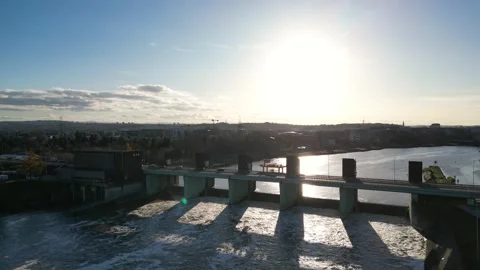 Aerial view of a dam spanning a river, showcasing flowing water and vehicles Stock Footage 323234909