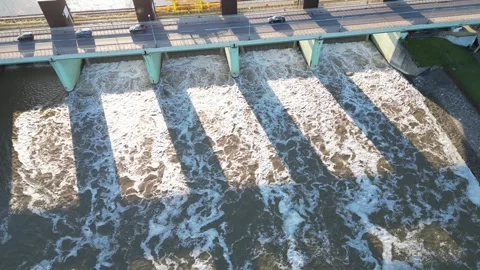 Aerial view of a dam spanning a river, showcasing flowing water and vehicles Video stock 335890727