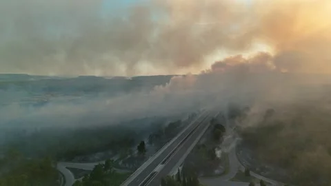 Aerial view of dangerous fire in the forest close to highway and village. Stock Footage 294073515