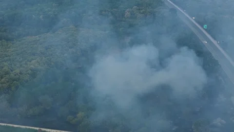 Aerial view of dangerous fire in the forest close to highway and village. Stock Footage 294077497