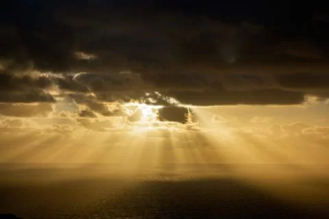 Aerial view of dark clouds back-lit by yellow evening sun over Tasman sea hor Stock Photos