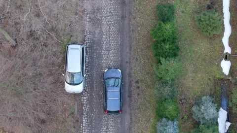 Aerial view of a dark graphite-colored station wagon navigating a muddy, pu.. Stock Footage 259158571