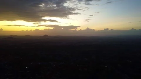 Aerial view of a dark landscape under a cloudy sky at sunset with a golden glow Stock Footage 313314559