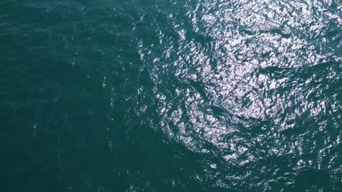 Aerial view of dark ocean surface with shimmering waves under daylight. Abstract Stock Footage 317377174