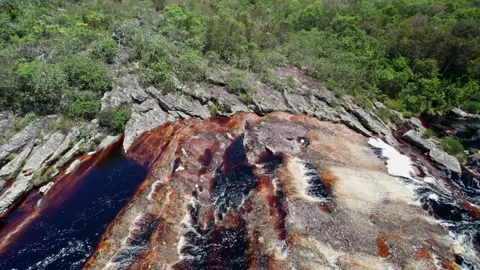 Aerial view of dark red river water flow over textured rock formations Stock Footage 332725169