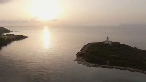 Aerial view at dawn over a lighthouse on a small island Stock Footage 129697744