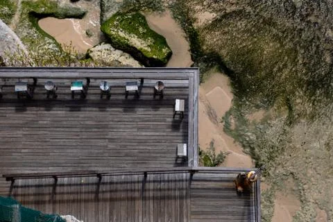 Aerial view of a decked seating area on a beach with a the sea coming in Stock Photos