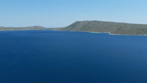 Aerial view of the deep blue Aegean Sea with the rugged, green coastline of Stock Footage 346706723