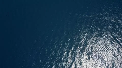 Aerial view of the deep blue ocean with sunlight reflecting off the water's Stock Footage 279661018