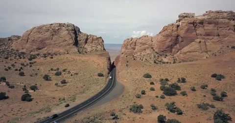 Aerial view of a deep notch cut into rock for desert highway with mobile home Stock Footage 119120049