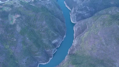 Aerial view of a deep river canyon winding through lush green mountain slopes Stock Footage 342231512