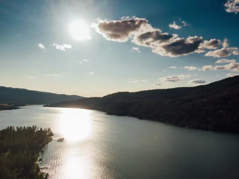 Aerial View of Dense Forest with River, Clouds, and Bright Sunlight Stock Footage 314693556