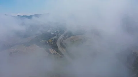 Aerial view descending through clouds to reveal busy road  v3 Stock Footage 119571889