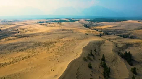 Aerial view of desert dunes with sparse vegetation and distant horizon Stock Footage 296264463