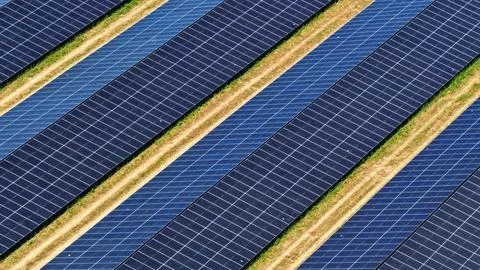 Aerial View of Diagonal Solar Panel Rows in Green Landscape Фото