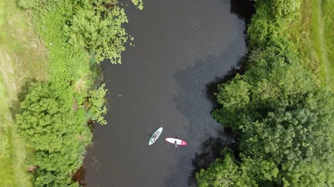 An aerial view from directly above of two paddle boarders slowly turning on a Stock Footage 157589615