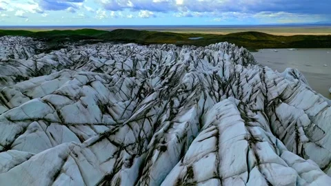 Aerial view of dirty glacier surface with deep crevasses and cracks near coastal Stock Footage 344241105
