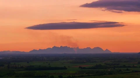 Aerial view of of distant mountain ridge under soft orange sunset sky with Stock Footage 314415164