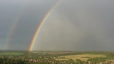 Aerial view of a double rainbow in the sky during rain,rainbow over villages and Stock Footage 154409323