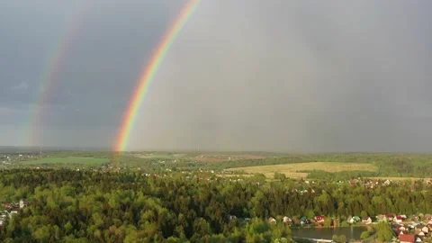 Aerial view of a double rainbow in the sky during rain,rainbow over villages and Stock Footage 155321425