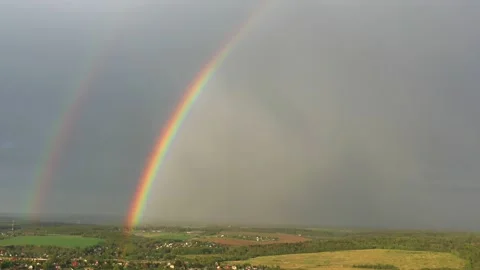 Aerial view of a double rainbow in the sky during rain,rainbow over villages and Stock Footage 159154754