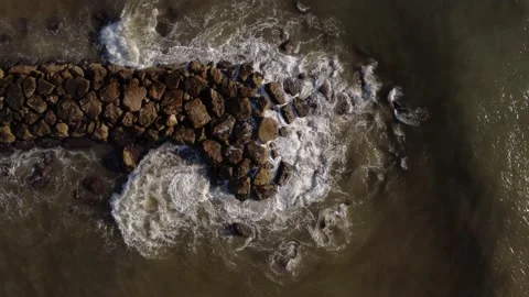 Aerial view down climbing from rocky breakwater into the sea Stock Footage 160093497