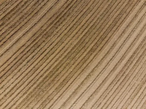 Aerial view down on empty barren field with very dry soil and plough furrows  Stock Photos