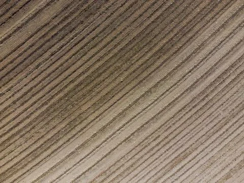 Aerial view down on empty barren field with very dry soil and plough furrows  Stock Photos