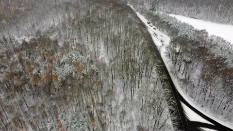 Aerial view down to snowy ground on road with cars, camera flies parallel t.. Stock Footage 228823402