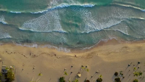 Aerial view down to the yellow beach and big waves. Descend down. Tourists lie Stock Footage 145155464
