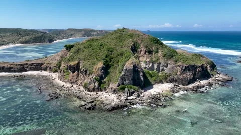 Aerial view of dramatic cliffs and a lush green hill on Lombok coast, surrounded Stock Footage 311205138