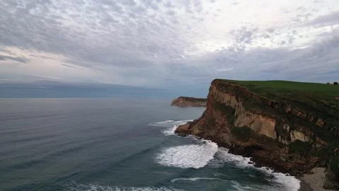 Aerial view of dramatic coastal cliffs and ocean under cloudy sky at dusk Stock Footage 317447844