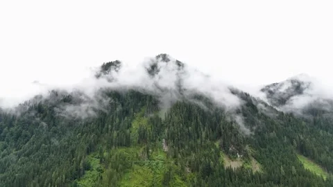 Aerial view of a dramatic mountain peak rising above moving clouds Stock Footage 322045496