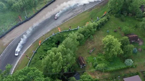 Aerial view of drifting car onA  curved racetrack with tire smoke Stock Footage 332109904