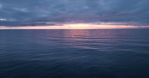 Aerial view of drone flight over the ocean during sunset, water surface in the Stock Footage 254678737
